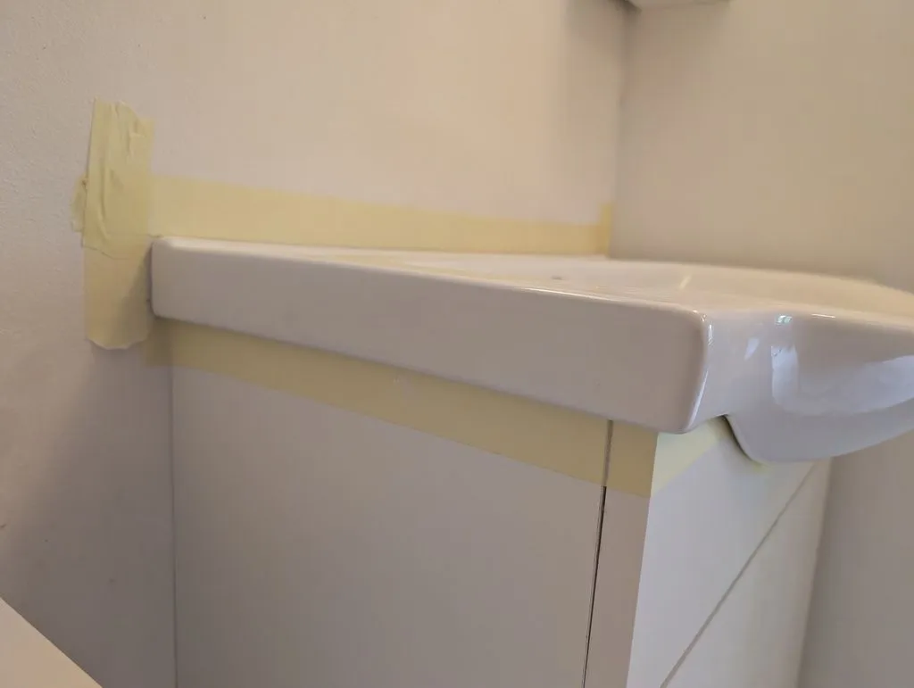 Test-fitting the sink before installing. The masking tape protects the area around the sink from the silicone sealant used to attach the sink to the base cabinet.