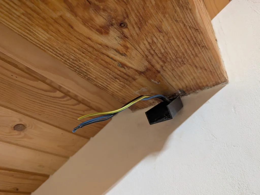 Electrical wire comes out of the wall at the beam to supply the track lights.