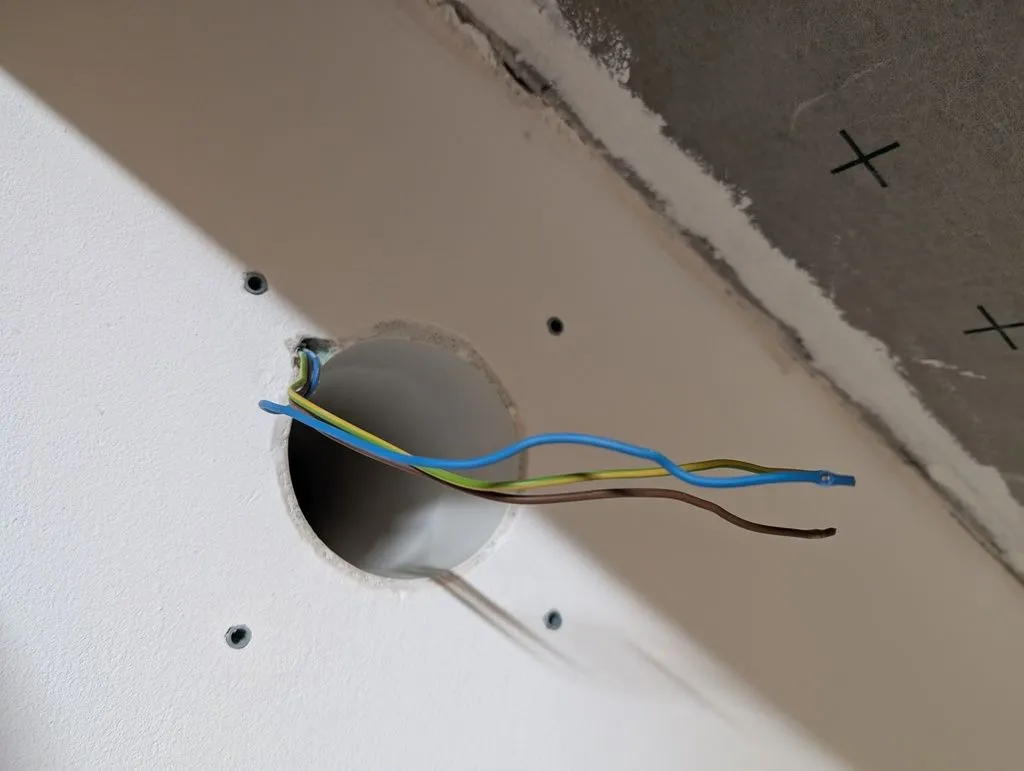 Supply conductors and ducting for the ventilation fan. The four holes in the wall are wall anchors for the ventilation's mounting frame.