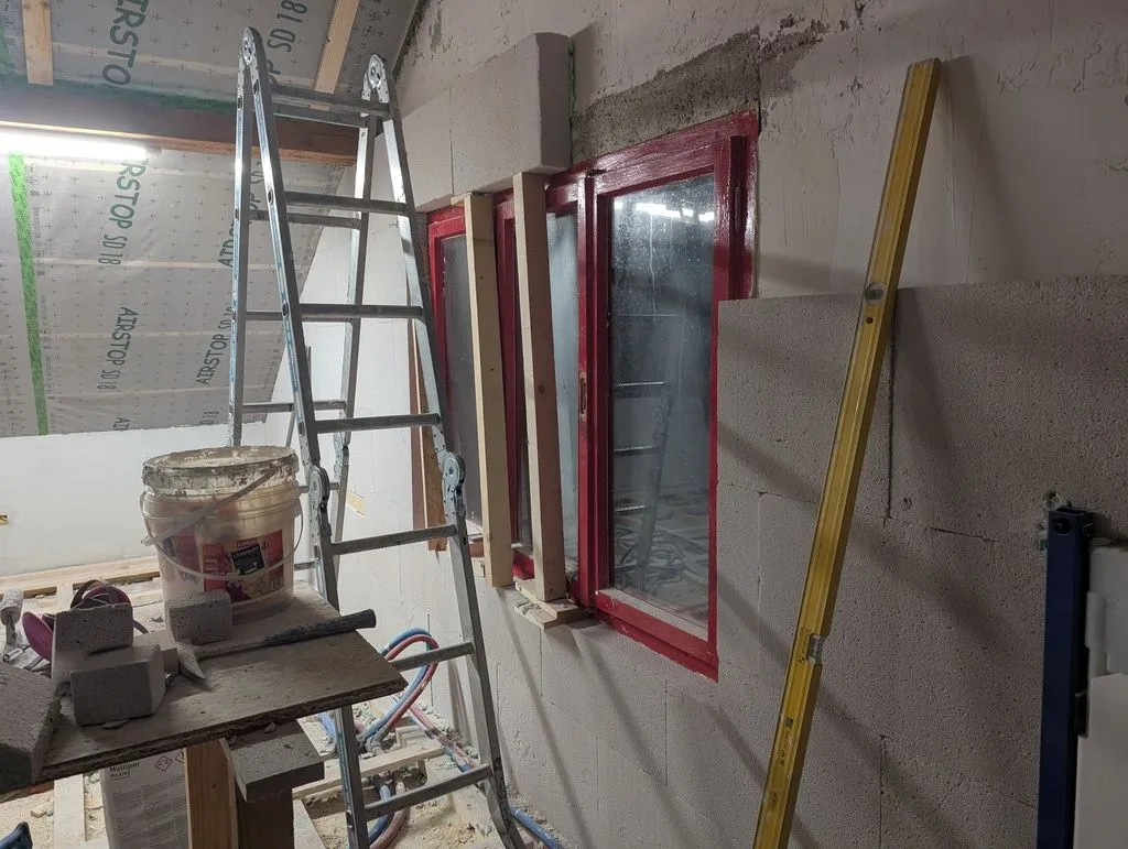 We used wood studs to temporarily support the Multipor above the window until the adhesive cured. The Multipor is light enough that no lintel is needed.