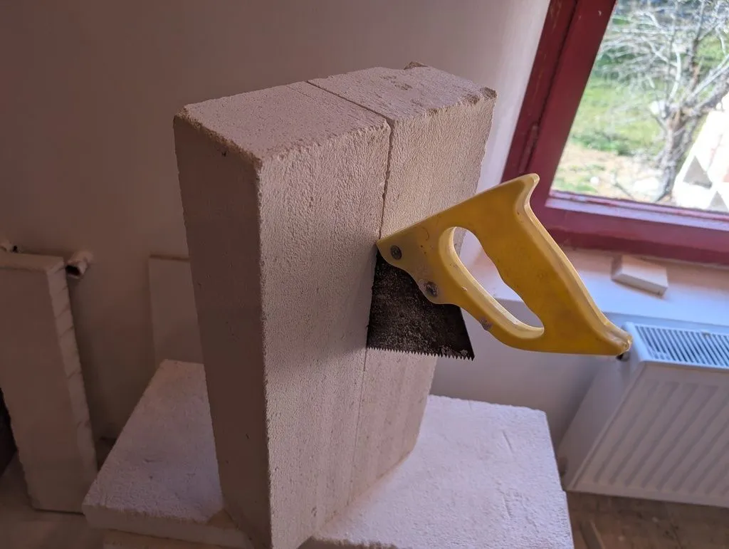 The aerated concrete blocks are cut without too much difficulty using hand saw (there a specialized saws for this purpose with large proprietary teeth, but a regular wood saw worked fine for me on this small-scale job).