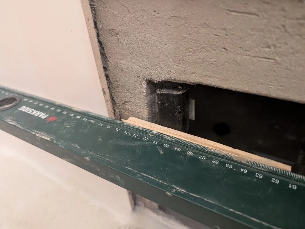 Using a straightedge with some wooden shims/gauges to judge the appropriate depth at which to attach the brackets so the blind tile will be flush with the rest of the wall.