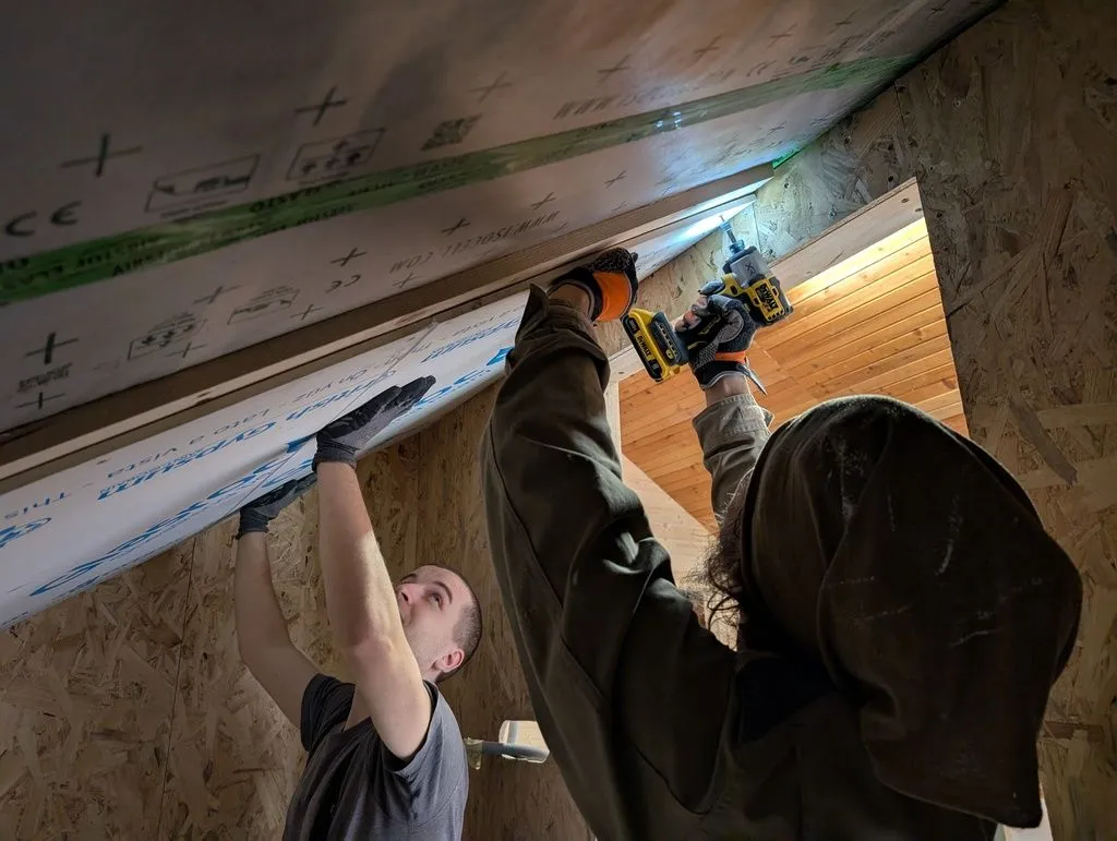 Anže attaching the ceiling drywall while I hold the board in place.