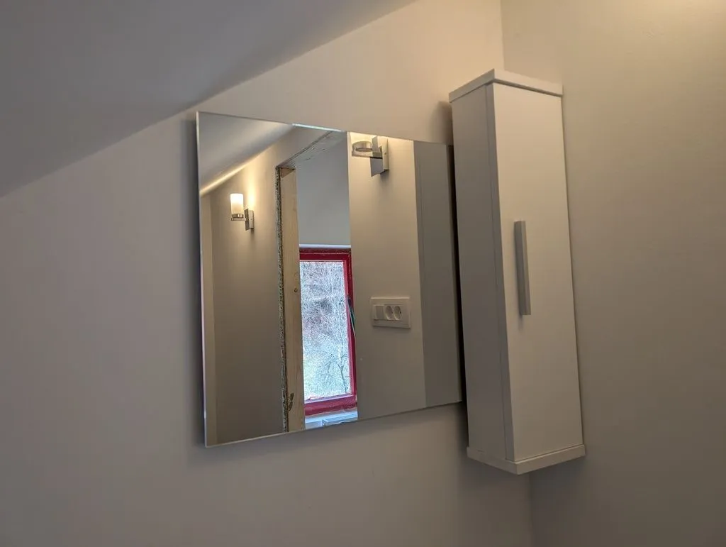 The installed mirror and cabinet. A cap piece holding an LED strip light will later go over the top of the mirror.