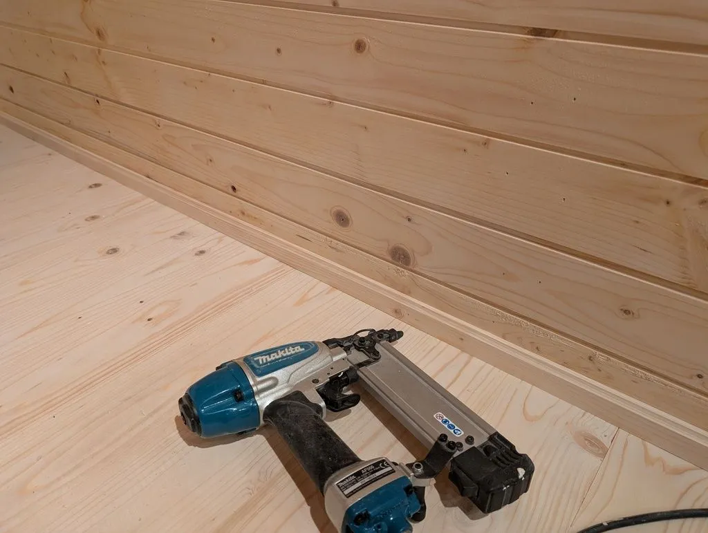 Attaching the baseboards to the wall using an 18 gauge brad nailer.