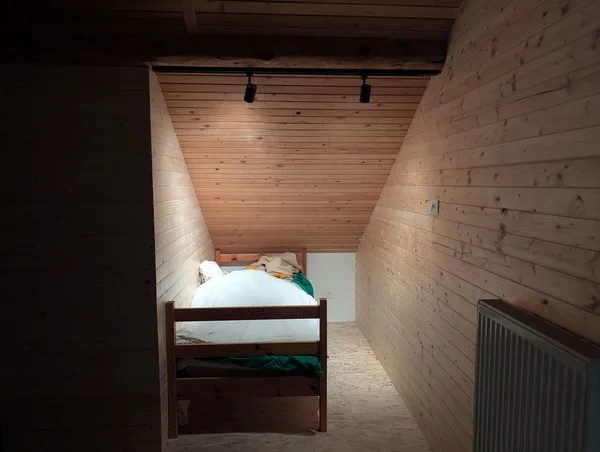 The sleeping nook in the attic apartment, lit by warm, cozy spotlights.