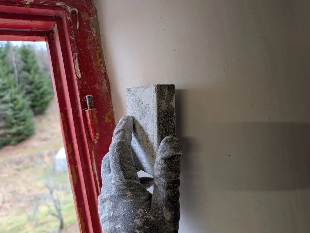 Sanding down rough spots with a drywall sanding block.