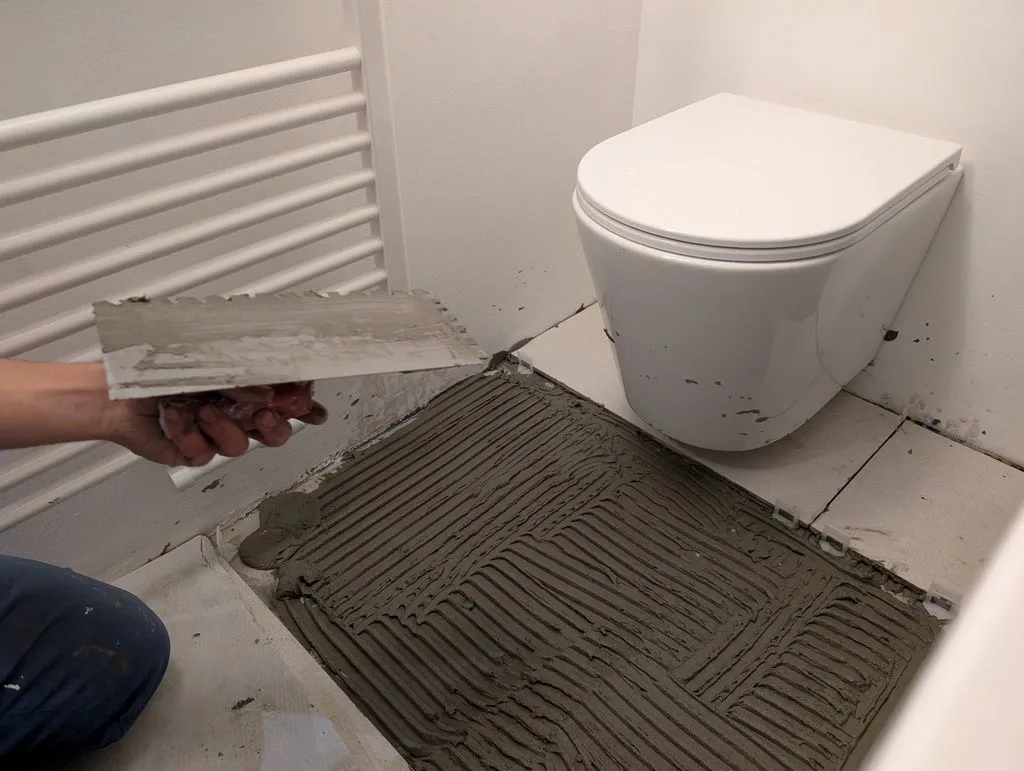 Completing the second phase of floor tiling—the suspended toilet makes it easy to tile under the toilet, as opposed to cutting tile to fit around a traditional floor-draining toilet. Notice how I am inexperienced and getting thinset everywhere—much more of that to come!