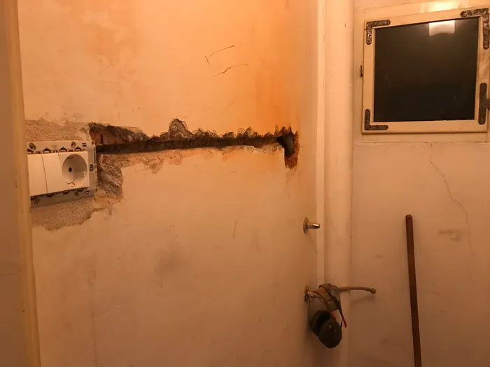 A new chase cut into the masonry wall to hold conduit and cable for a second outlet.