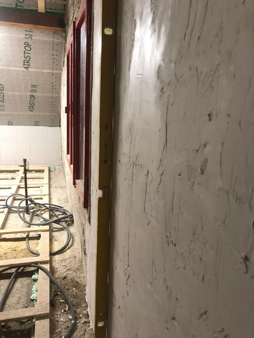 The wall after rough leveling—note that the gaps under the straight level are now minimal compared to the original state.