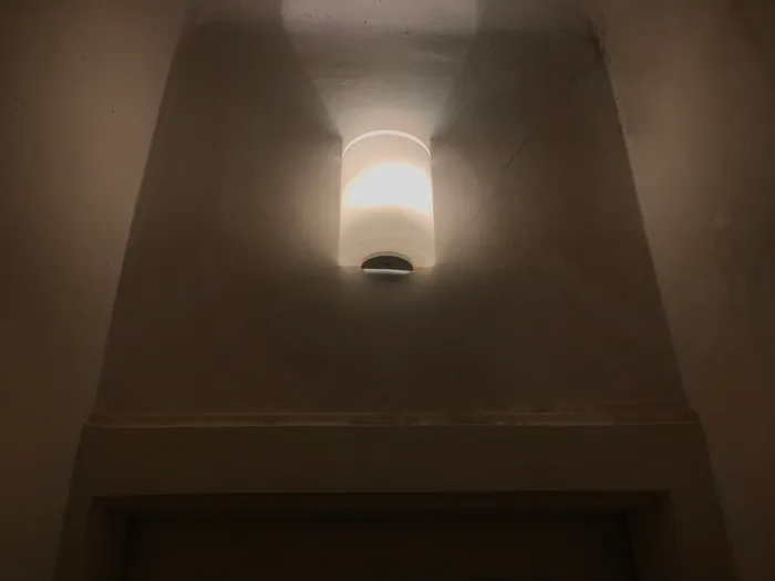 The new wall-mounted light fixture replacing the original bare lightbulb.