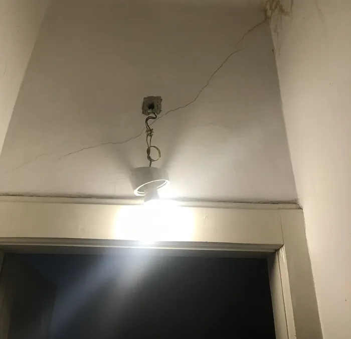 The original bare lightbulb, seen dangling from the wall by its supply wires.