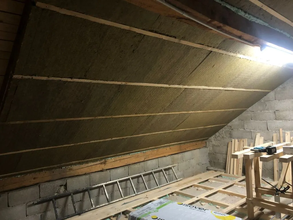 The final layer of rock wool installed. This layer is placed continuously over the entire surface of the ceiling, eliminating thermal bridging through the rafters.
