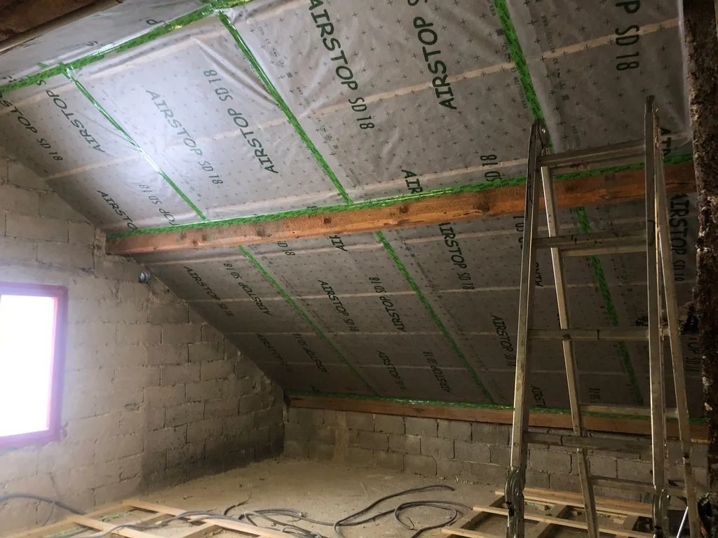 The vapor barrier placed over the insulation, with seams taped. The roof is now ready for the finish ceiling.